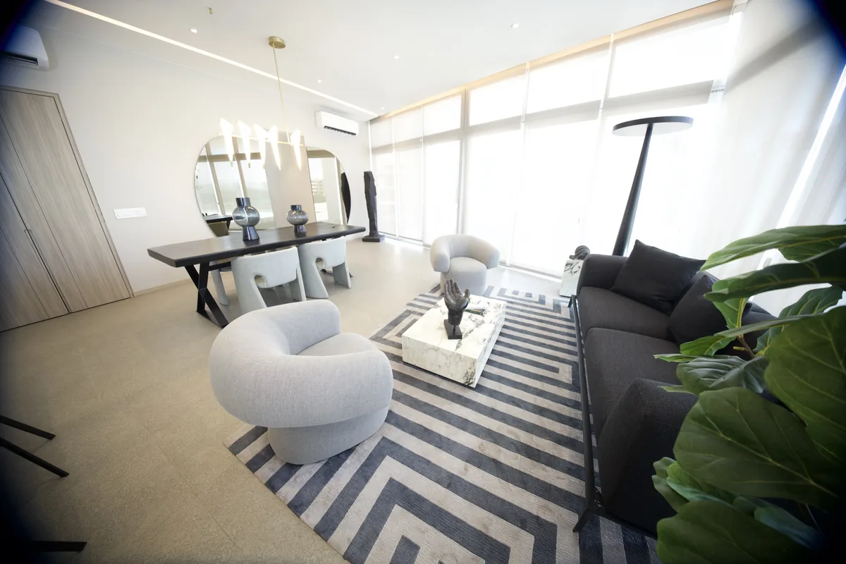 Sala del departamento muestra con ventanales de piso a techo